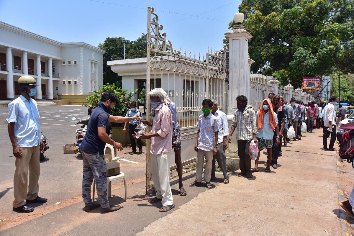 Hotelier Hariprasad Shetty, with the support of fire personnel, serves food to destitutes near Town Hall in Mangaluru. DH PHOTO/Govindraj Javali