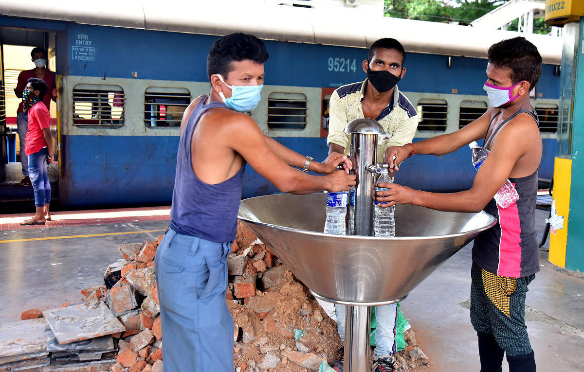 Stranded migrant labourers fill water bottles before leaving for Prayagraj from Mangaluru Junction Railway Station on Tuesday.