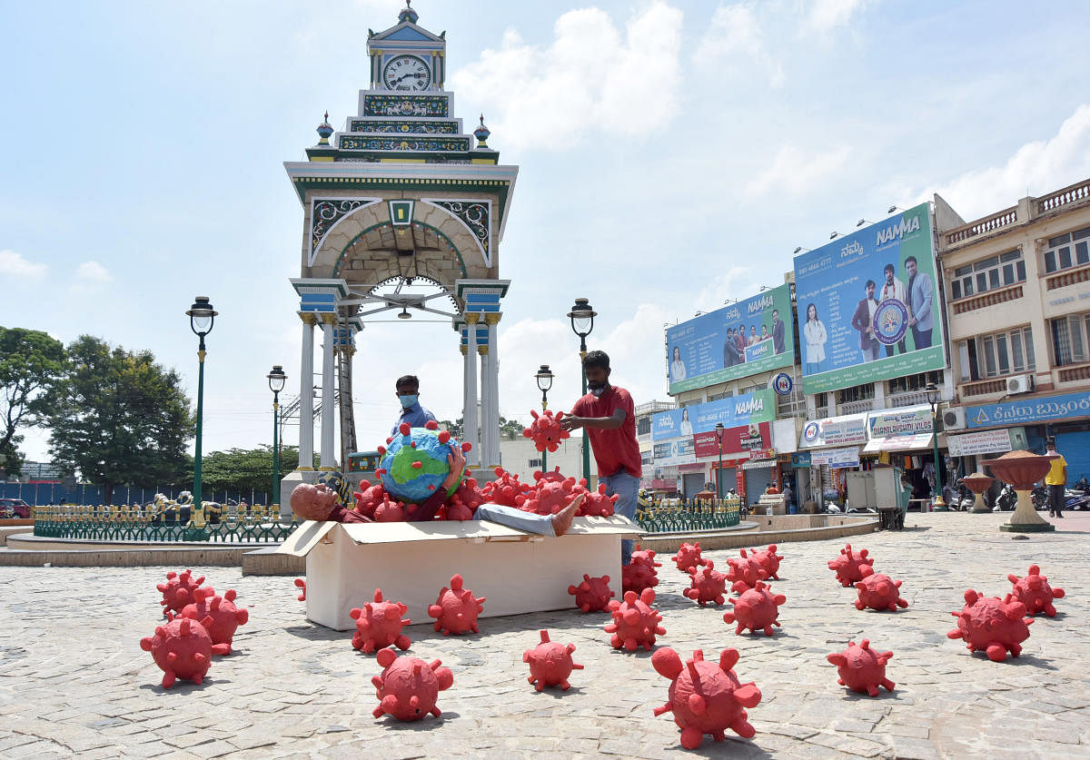 Artist Prasanna Kumar displays an artwork to create awareness against Covid-19 near Dufferin Clock in Mysuru on Thursday.