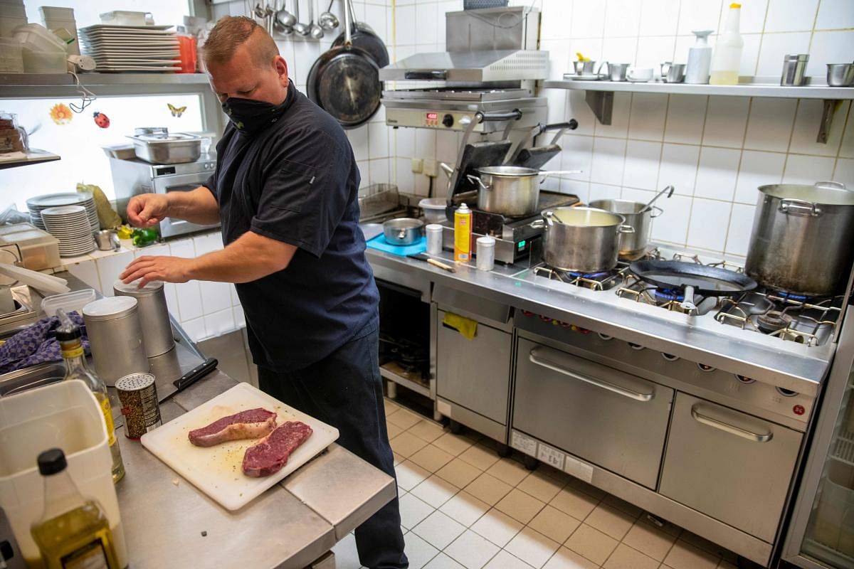 Chef Radeke prepares meat in the kitchen of the reopened Cafe Prag in Schwerin, northeastern Germany. AFP