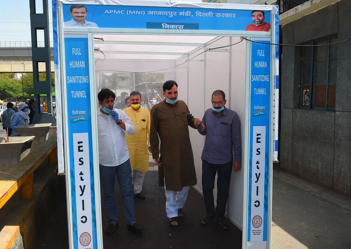  Delhi Labour Minister Gopal Rai with Azadpur Mandi Chairman Adil Ahmad Khan walk through a sanitizing tunnel after its installation, during the nationwide lockdown to curb the spread of coronavirus, at Azadpur Mandi in New Delhi. PTI