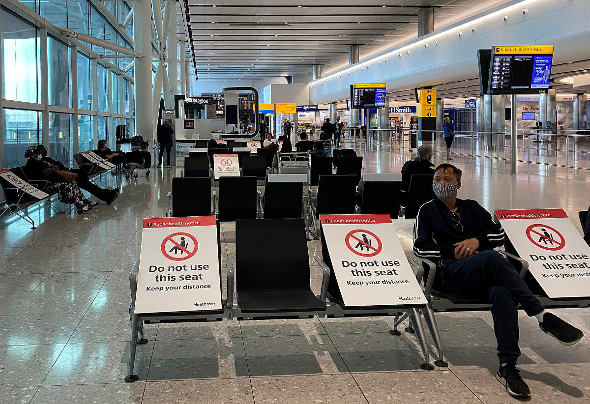 People sit amongst socially distanced seating signs at Heathrow Airport, as the spread of the coronavirus disease (COVID-19) continues, in London, Britain, May 10, 2020. Credit: Reuters Photo