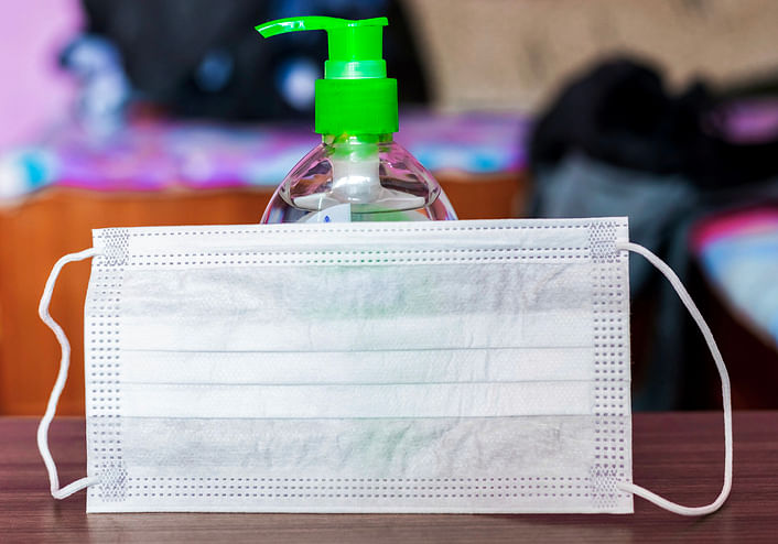 Disposable paper mask placed infront of a bottle of hand sanitizer.(iStock Photo)