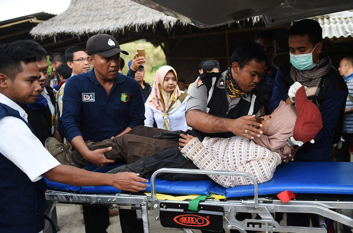 Rescue team members give treatment to a climber after walking down from Rinjani Mountain at Sembalun village in Lombok Timur, Indonesia, July 30, 2018. Antara Foto/Akbar Nugroho Gumay/Reuters