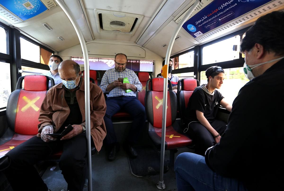 Iranian men keep distance from each other while sitting at a bus in Tehran (AFP Photo)