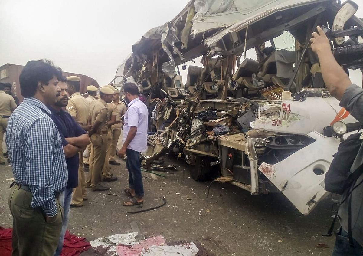 Passersby and policemen stand near the mangled remains of Kerala State Road Transport Corporation bus which collided head-on with a container lorry near Tamil Nadu's Avinashi town. PTI