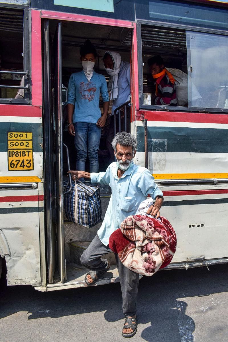  Migrant labourers from Uttar Pradesh who were stranded in Haryana alight from the bus arranged by UP government (PTI Photo)