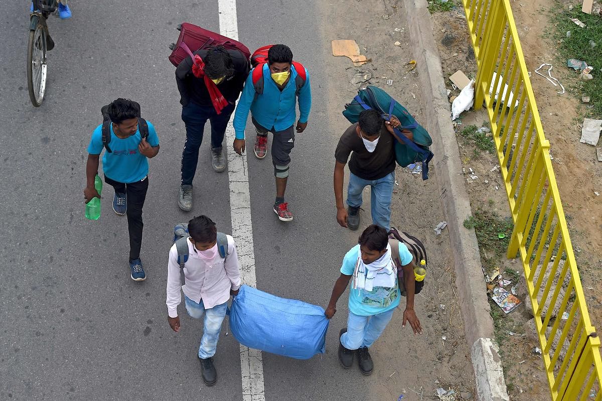 Migrant workers and their family members walk with their belongings towards their respective hometown states (AFP Photo)
