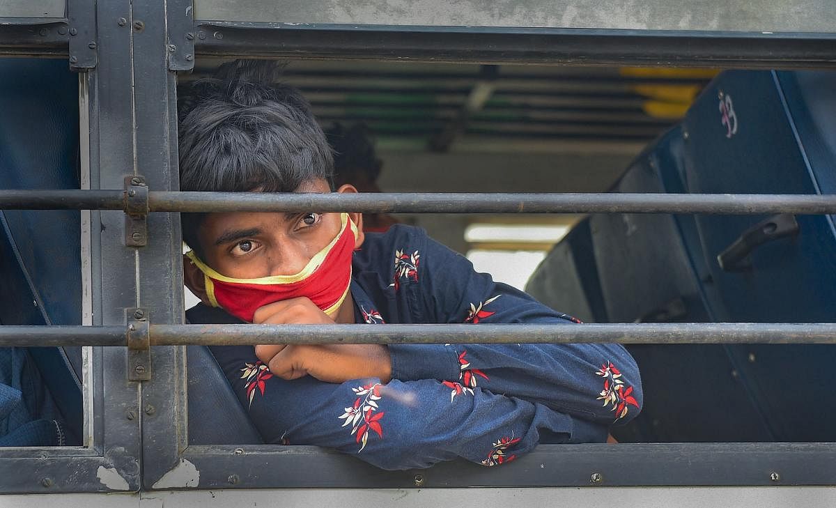  A migrant worker wearing a mask looks through a window of a bus to reach his native place, during the ongoing nationwide COVID-19 lockdown, in Kolkata, Wednesday, April 29, 2020. (PTI Photo)