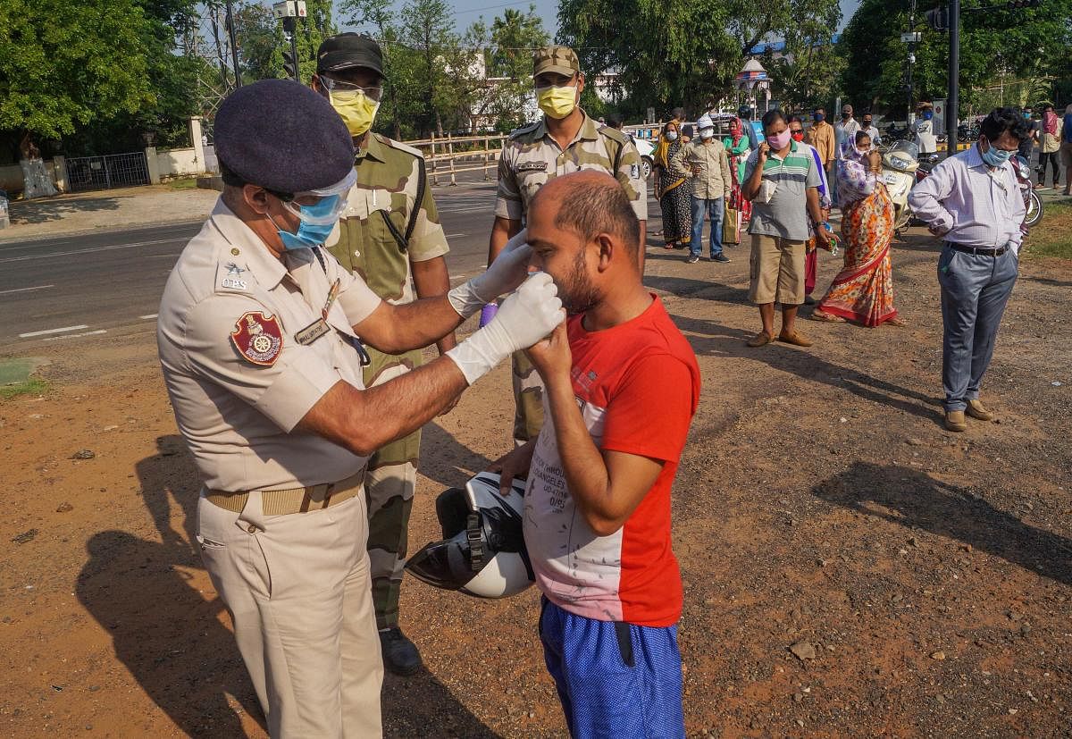 A policeman helps a man wear his facemask (PTI Photo)