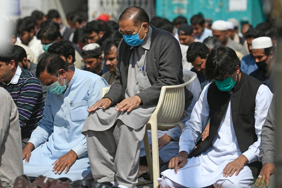 Muslim men wearing facemasks amid concerns over the spread of the COVID-19 novel coronavirus, offer Friday prayers along the roadside in Islamabad(AFP Photo)
