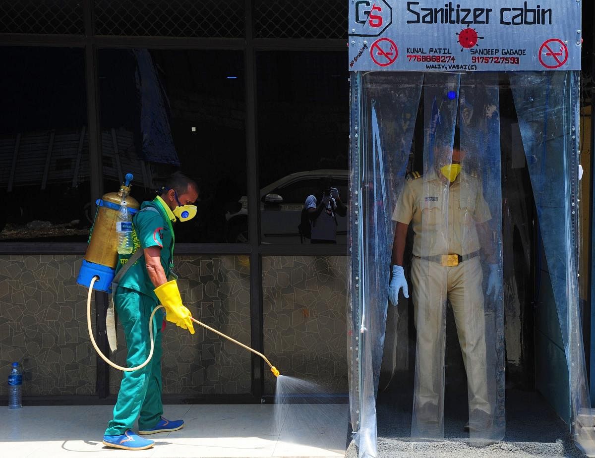 A worker sprays disinfectant outside a sanitizer cabin to curb the spread of coronavirus, during the nationwide lockdown, in Palghar, Friday, April 10, 2020. (PTI Photo)
