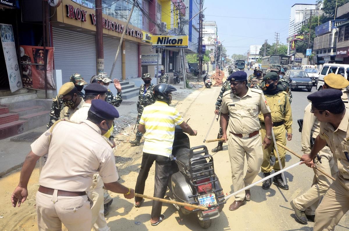 Police personnel (L) beat a scooterist with batons as they enforce complete lockdown for containing the spread of the novel coronavirus. PTI