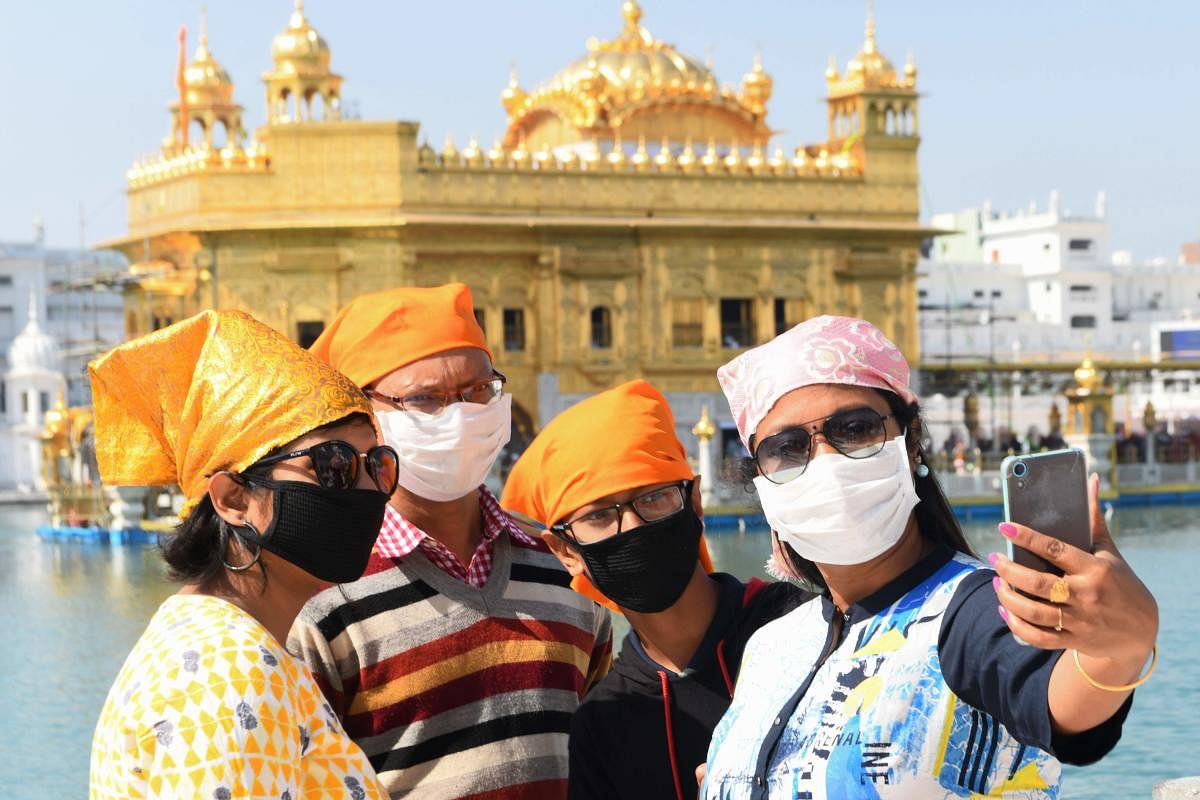 Devotees wearing a facemask amid concerns over the spread of the COVID-19 coronavirus take a selfie at the Golden Temple in Amritsar on March 17, 2020. Credit: AFP Photo
