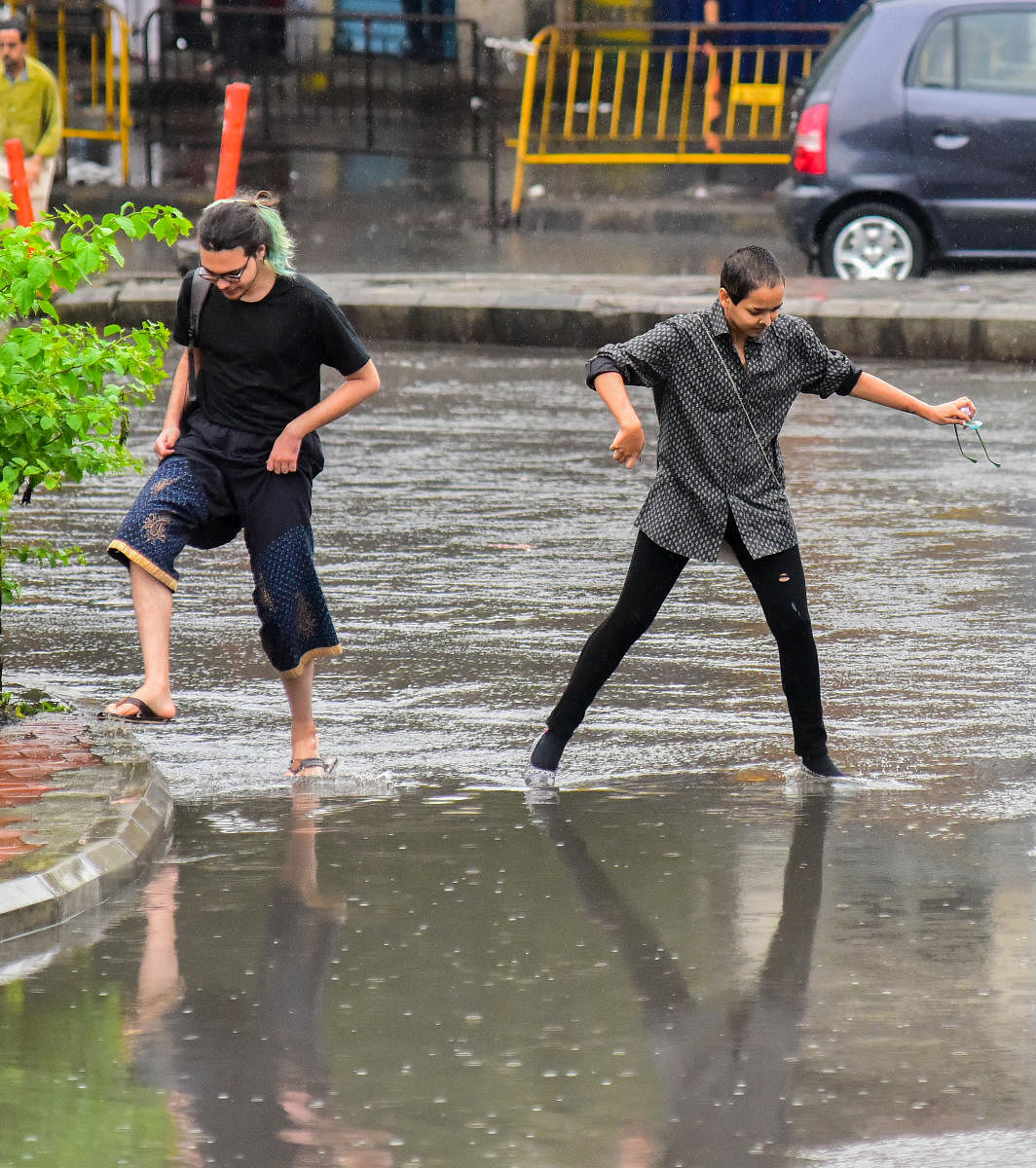Two people negotiate a rain-filled road near Town Hall. DH PHOTO/ANUP RAGH T 