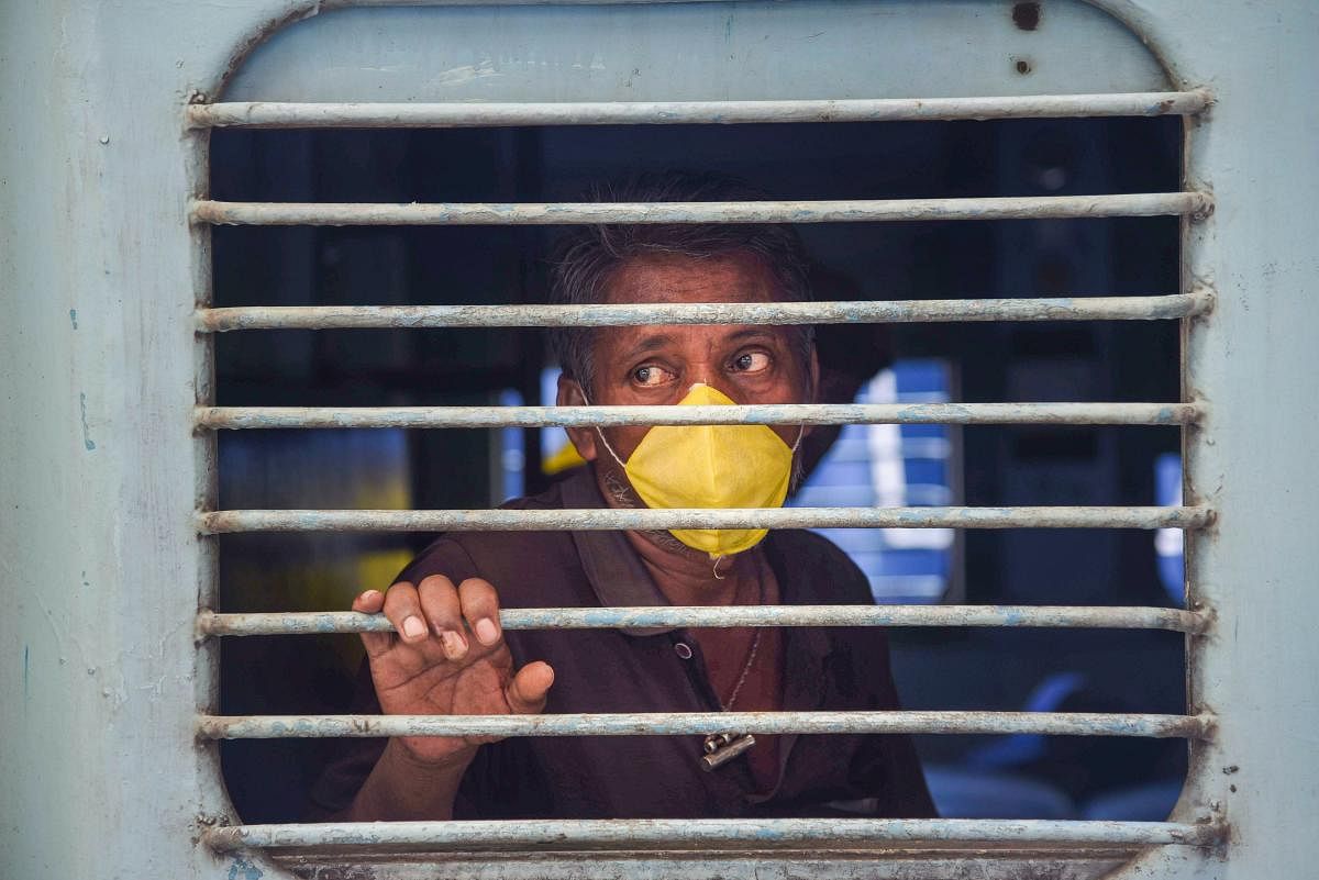 A migrant looks through a window during his departure for Odisha by 'Shramik Special' train at Panvel Railway Station, amid the ongoing COVID-19 nationwide lockdown, in Navi Mumbai, Saturday, May 9, 2020. (PTI Photo)