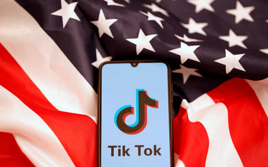 Tik Tok logo is displayed on the smartphone while standing on the U.S. flag in this illustration. (Credit: Reuters)
