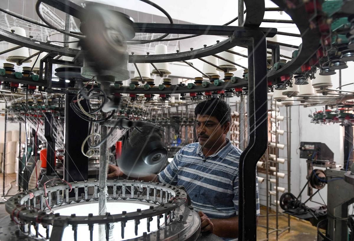 A factory worker works on a fabricating machine at a textile production unit in Tiruppur. AFP
