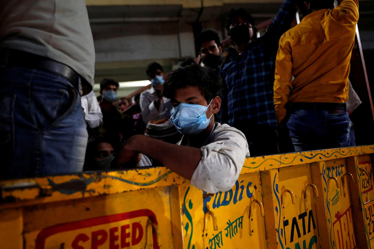 Migrant workers wearing protective face masks ride a Tempo which will get them across the border to their home state of Uttar Pradesh, during an extended nationwide lockdown to slow the spread of the coronavirus disease (COVID-19), in New Delhi, India, May 16, 2020. Credit: Reuters Photo