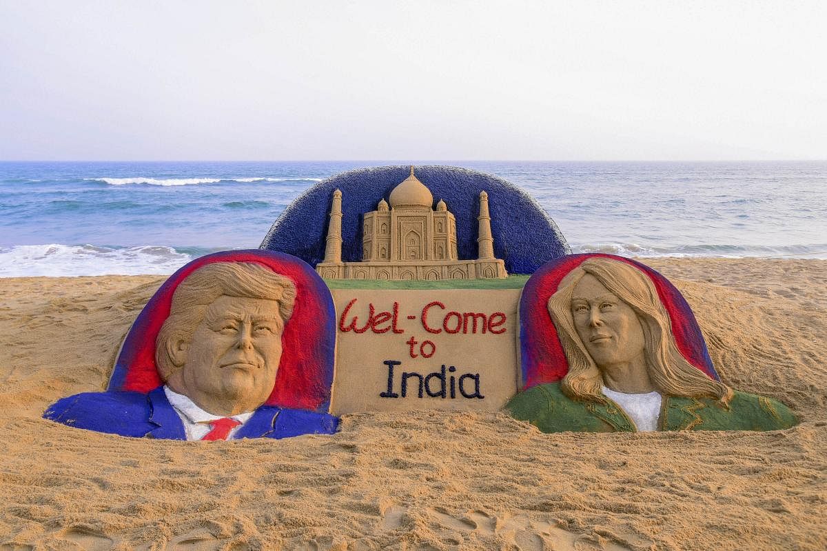 Tourists look on at a sand sculpture on US President Donald Trump with First Lady Melania Trump ahead of their maiden India visit, in Puri, Saturday, Feb. 22, 2020. (PTI Photo)