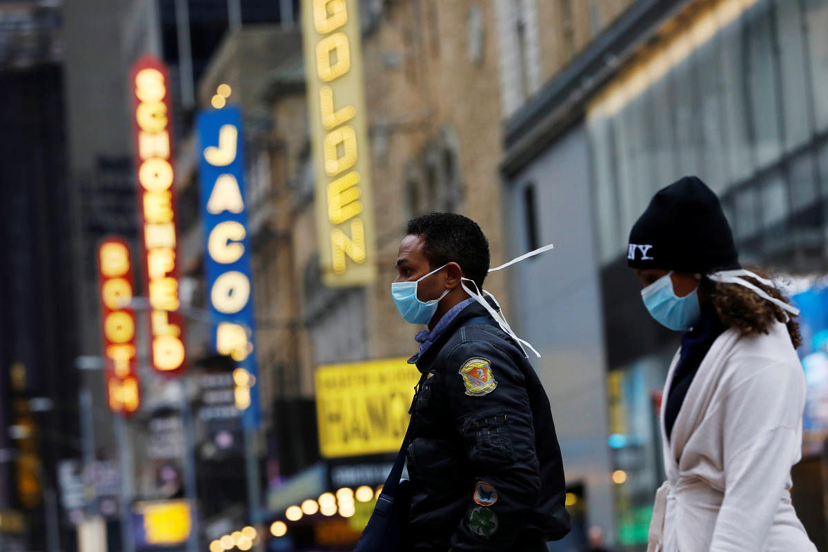 People in surgical masks walk through Manhattan's Broadway Theatre district after Broadway shows announced they will cancel performances due to the coronavirus outbreak in Manhattan, New York City, New York. Credit: Reuters Photo
