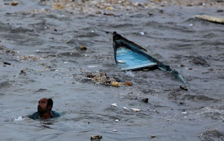 A fisherman swims to shore after his boat capsized due to high waves ahead of the expected landfall of Cyclone Vayu at Veraval, India, June 12, 2019. REUTERS/Amit Dave