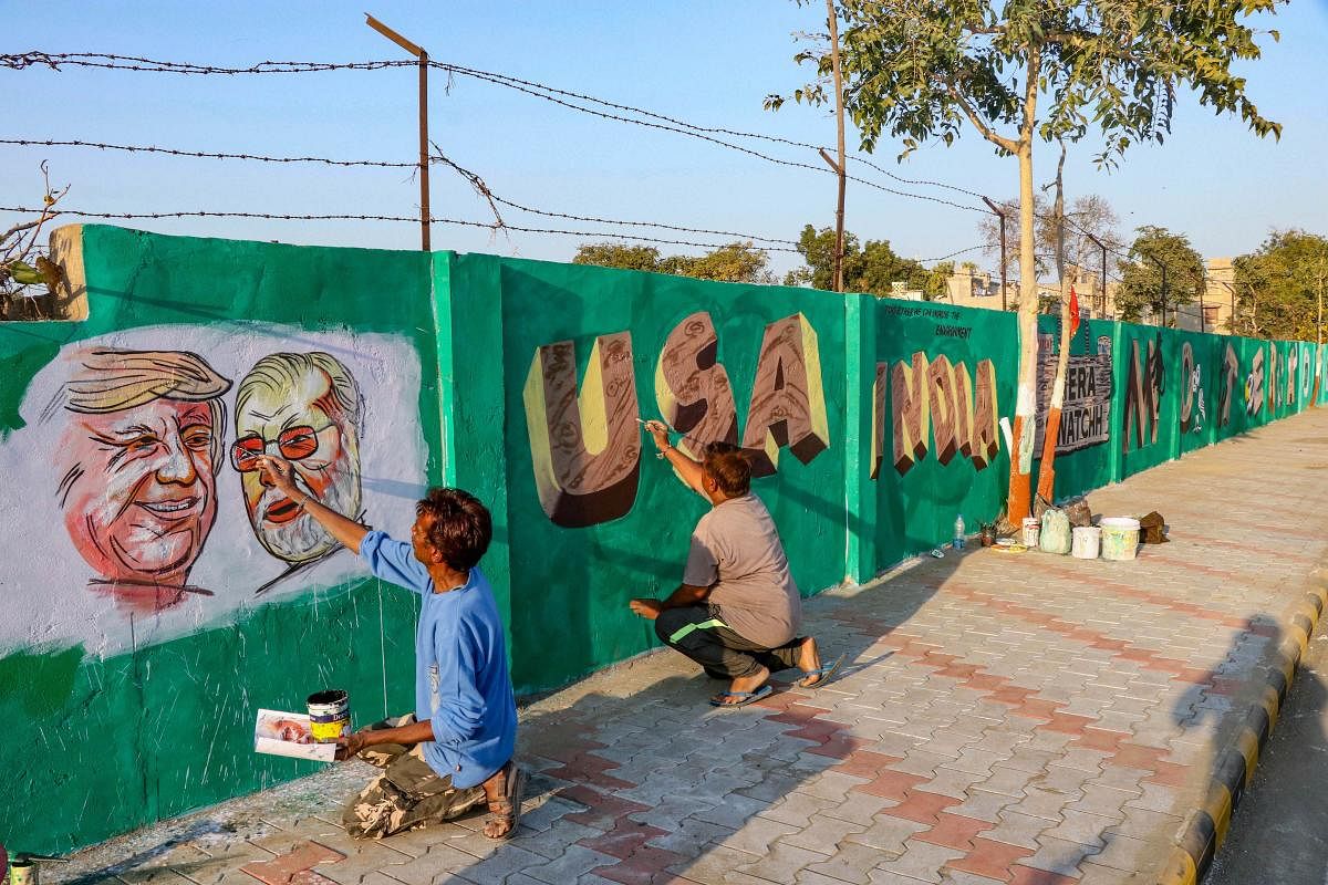 Men applies finishing touches to paintings of U.S. President Donald Trump and India's Prime Minister Narendra Modi on a wall as part of a beautification along a route that Trump and Modi will be taking during Trump's upcoming visit, in Ahmedabad, Monday, Feb. 17, 2020. (PTI Photo)