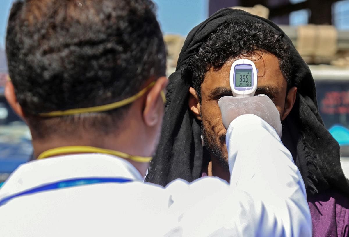 A health official checks the body temperature of man at the entrance of the city of Taez in southwestern Yemen in the wake of COVID-19 outbreak (AFP Photo)