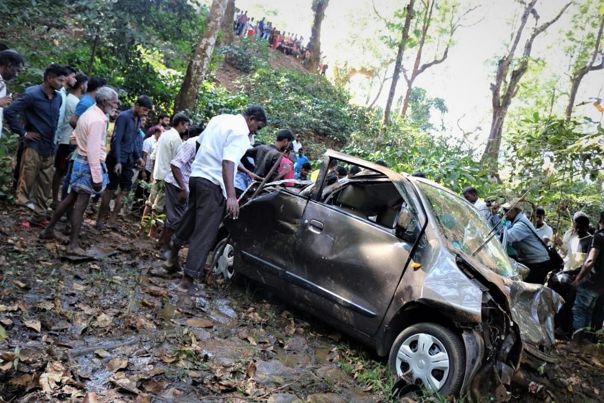 Locals look at the car which had rolled down a 50-foot-deep gorge near Hirebailu in Kalasa taluk, Chikkamagaluru, on Monday.