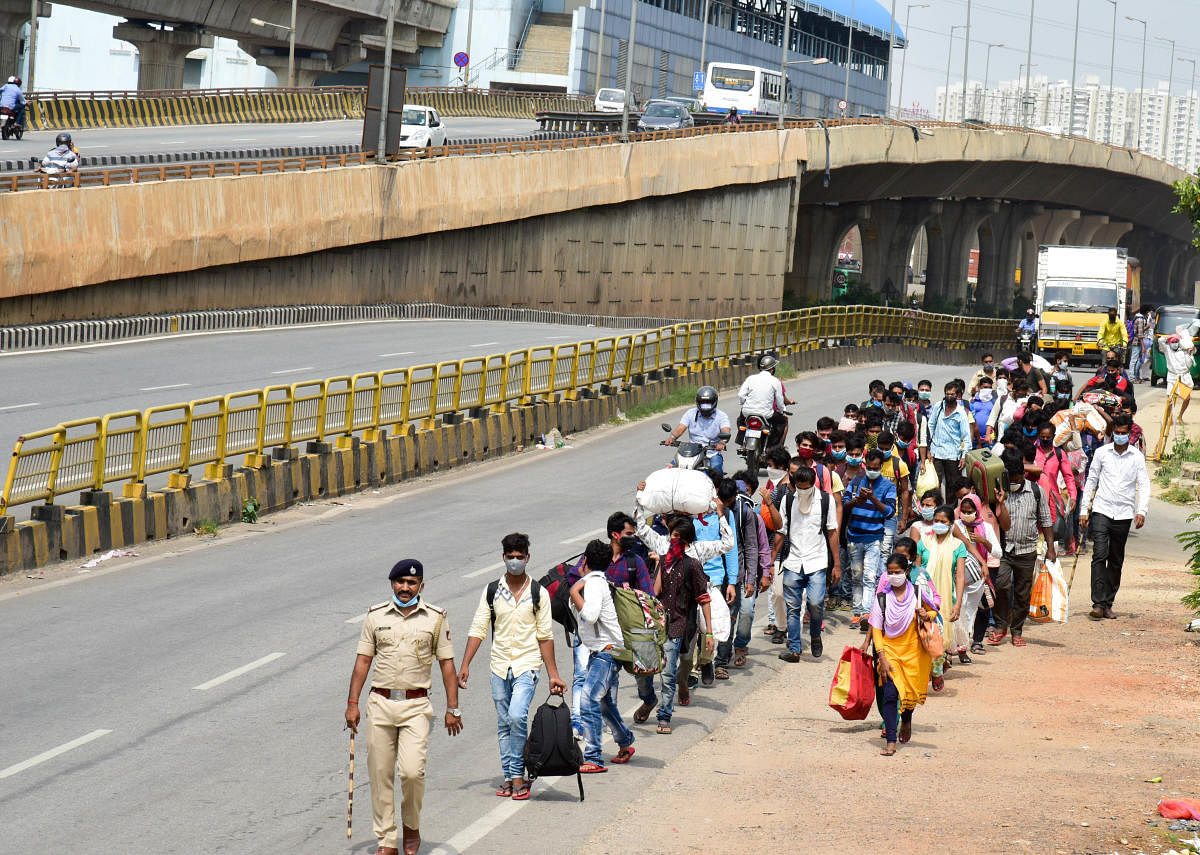 Police escort migrants from BIEC to the Radha Soami Satsang Beas ashram on Tuesday. DH PHOTO/B H SHIVAKUMAR