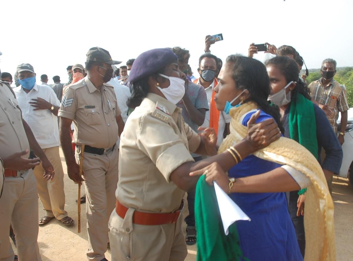 A woman police personnel pacifies an activist of Raitha Sangha and Hasiru Sene during the visit of Minor Irrigation Minister J C Madhuswamy to S Agrahara village in Kolar taluk on Wednesday. DH Photo