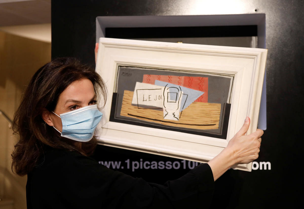 Raffle organizer Peri Cochin, wearing a protective face mask, poses with the painting "Nature Morte, 1921" by Spanish painter Pablo Picasso. (Reuters photo)