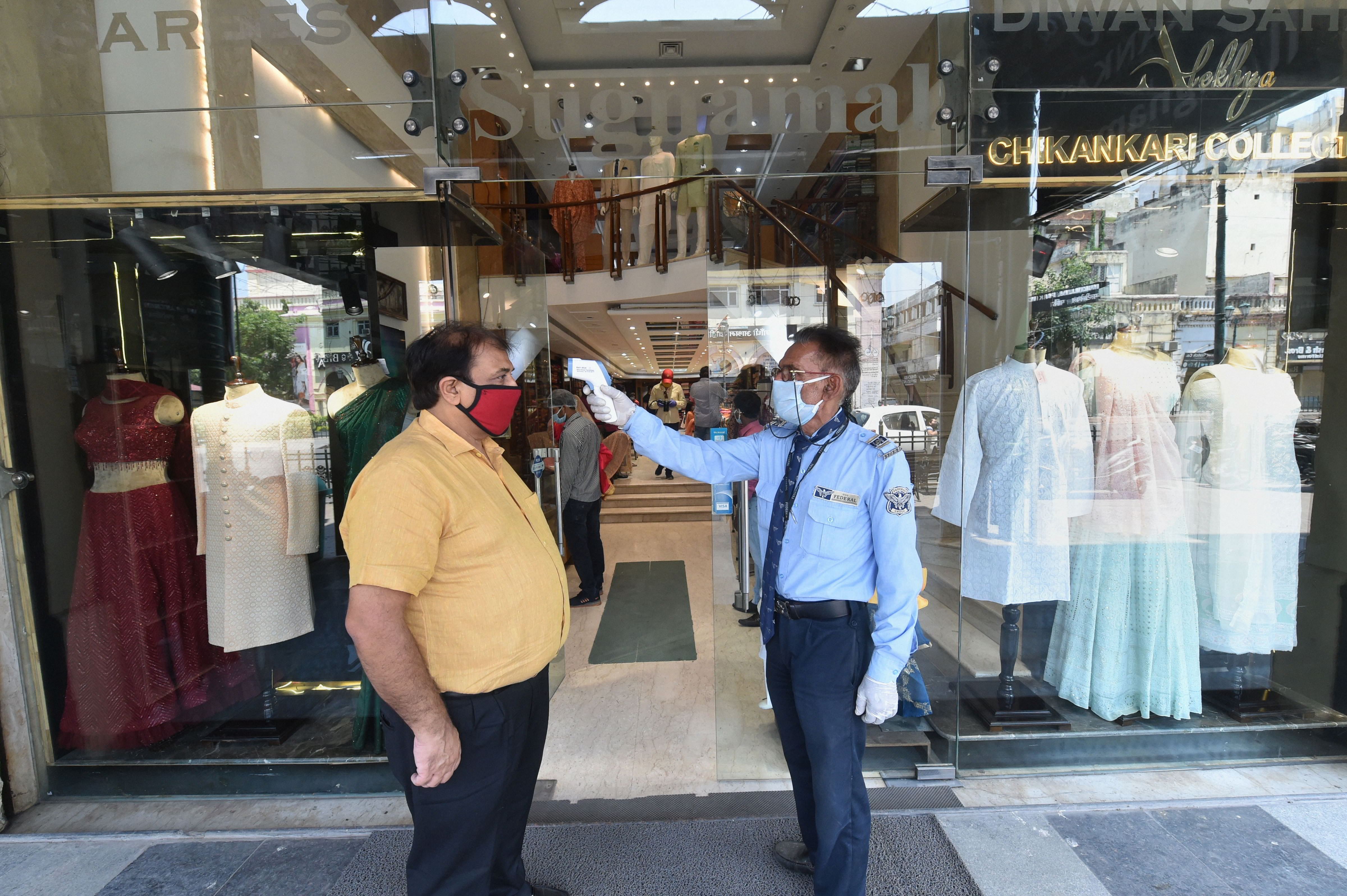 : A guard checks the temperature of a customer entering a clothing store after resumption of activities in non-containment zones, during the fourth phase of COVID-19. (PTI Photo)