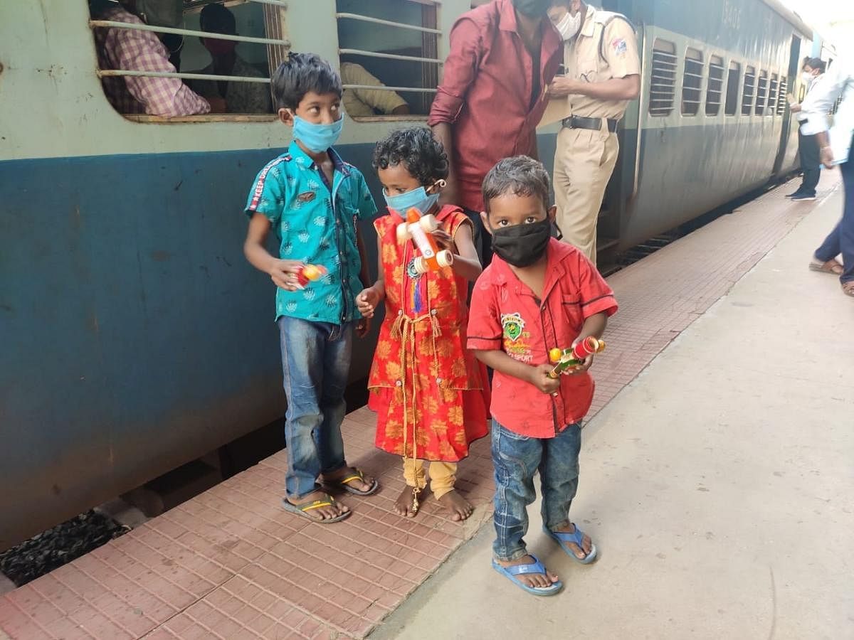 Children of migrant workers pose with Channapatna toys from inside a train in Bengaluru.   DH Photo