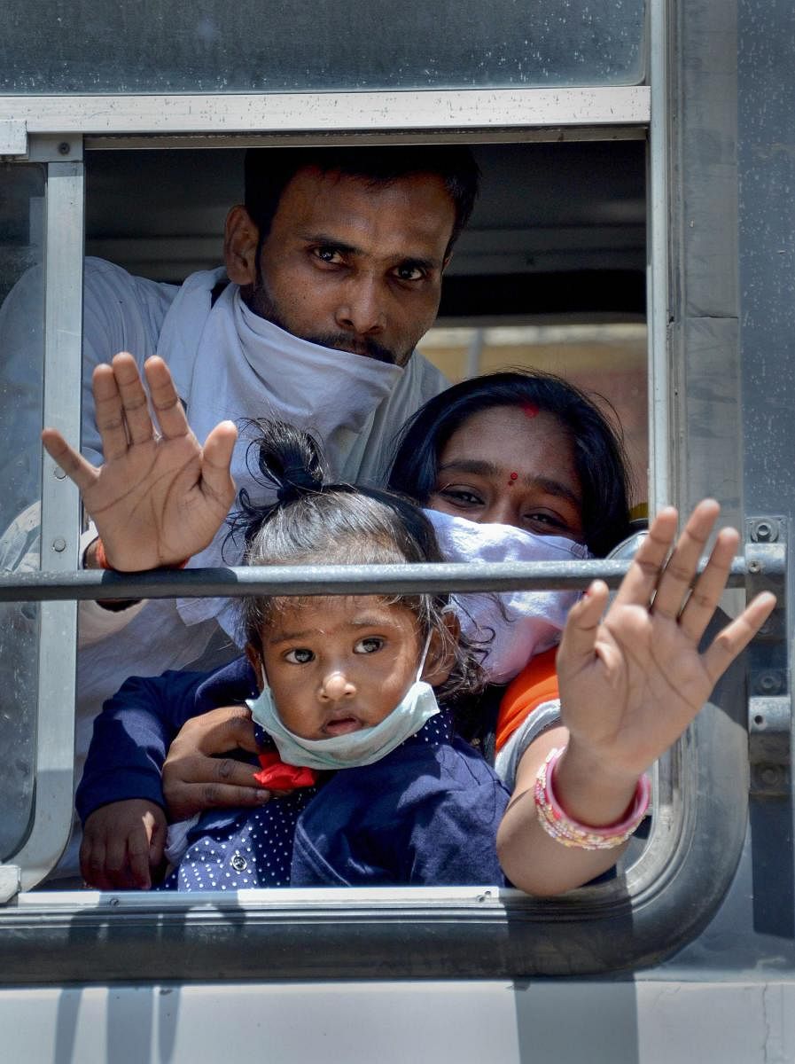 Amritsar: Migrants wave as they leave in a bus for railway station, to board a train to Uttar Pradesh, during ongoing COVID-19 lockdown, in Amritsar, Wednesday, May 20, 2020. (PTI Photo) (PTI20-05-2020_000255A)
