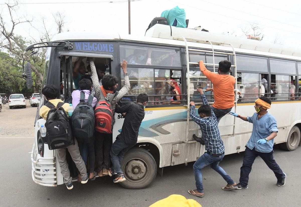 Migrants board a bus to reach their native places after arriving from various states by special train, during ongoing COVID-19 lockdown, in Patna. PTI
