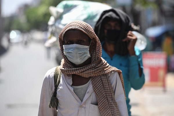 Migrant workers stand in a line waiting to be moved to a shelter home as the government eased a nationwide lockdown as a preventive measure against the COVID-19 coronavirus, in Ghaziabad on May 20, 2020. (AFP Photo/Prakash Singh)