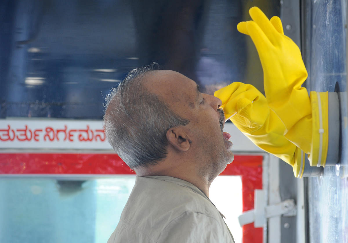 Medical staff conduct tests with the help of a COVID-19 mobile testing unit at Padarayanapura in Bengaluru on Friday. DH Photo/ Pushkar V