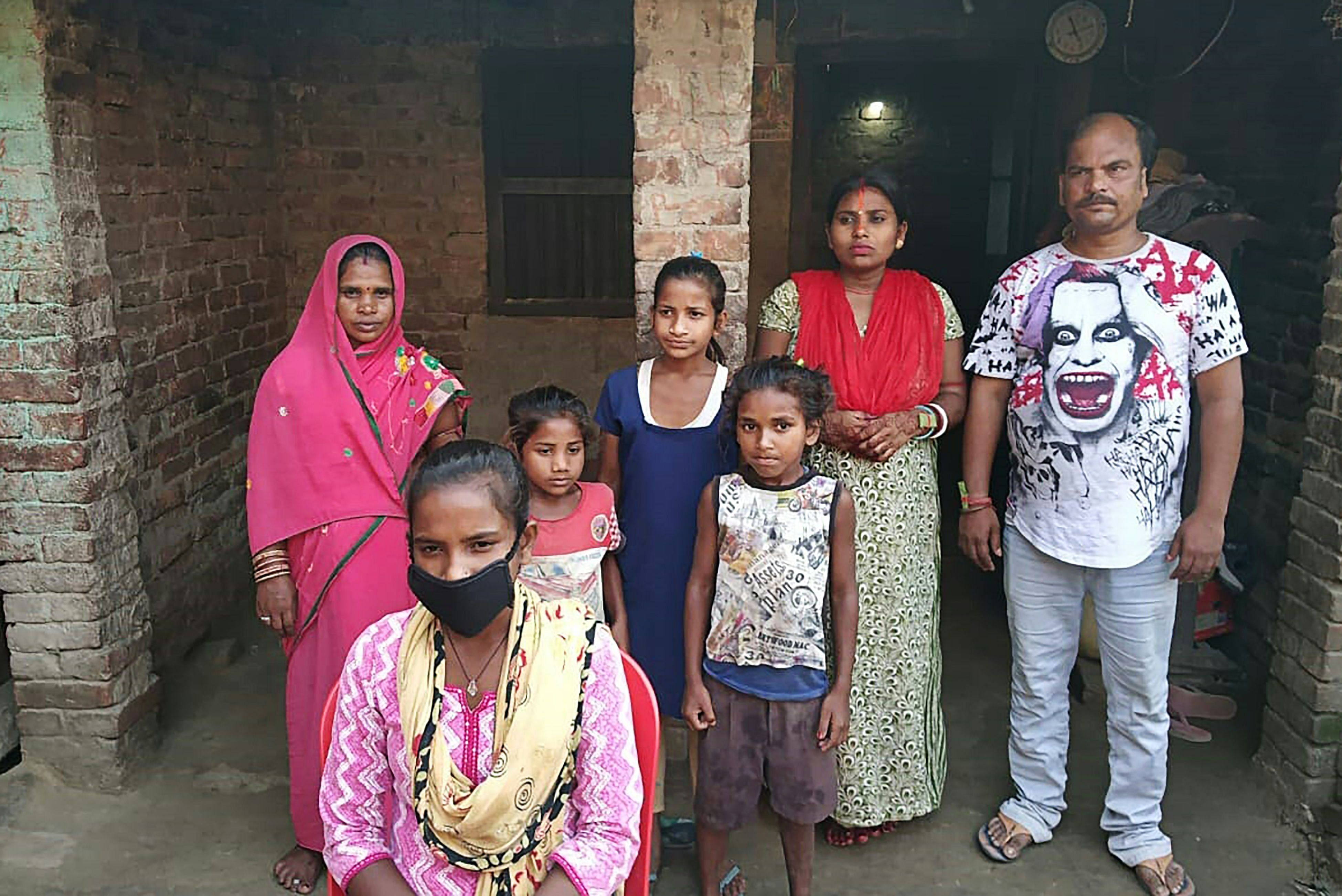 yoti Kumari Paswan (C-bottom) and her family stand in front of their house in Siruhully village at Darbhanga district. (AFP Photo)