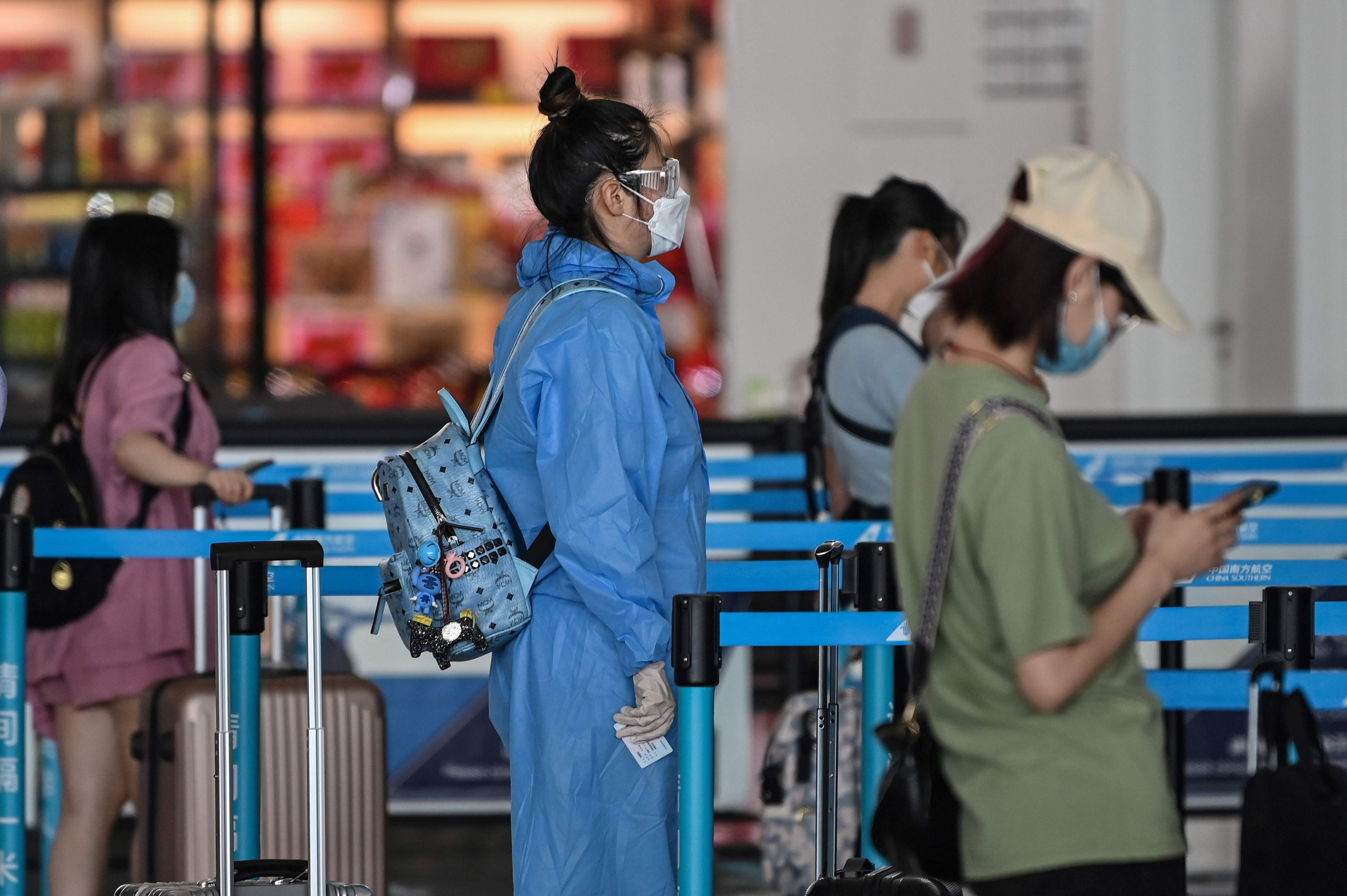 A passenger wearing a protective gear and a face mask waits in line at an airline counter at Tianhe airport in Wuhan. (Credit: AFP Photo)