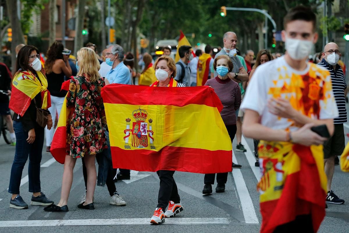 Demonstrators hold up Spanish flags during a protest on May 20, 2020, in Barcelona, against the Spanish government's measures during the national lockdown to prevent the spread of the COVID-19 disease. Credit: AFP Photo