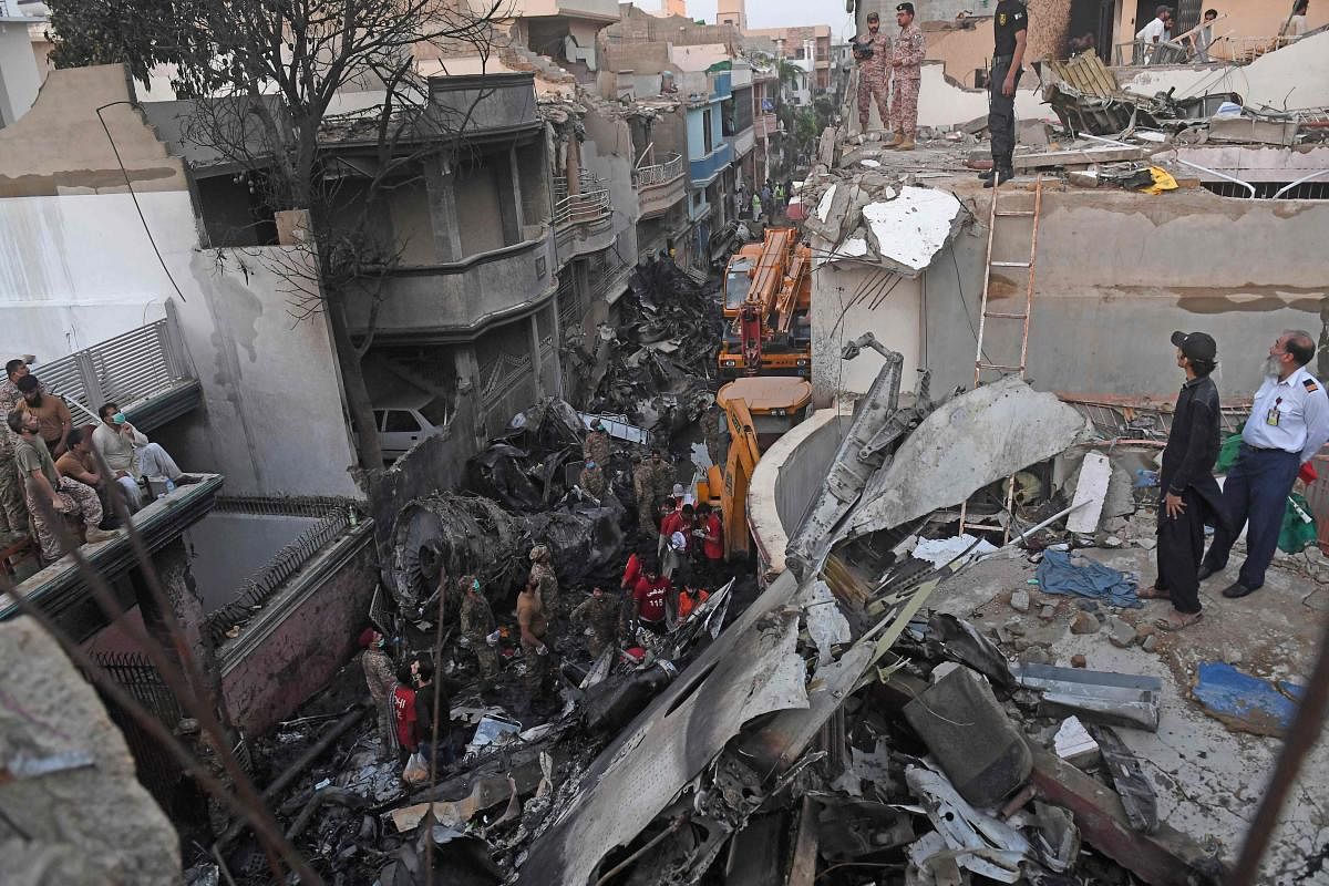  Security personnel search for victims in the wreckage of a Pakistan International Airlines aircraft after it crashed in a residential area in Karachi. (AFP Photo)