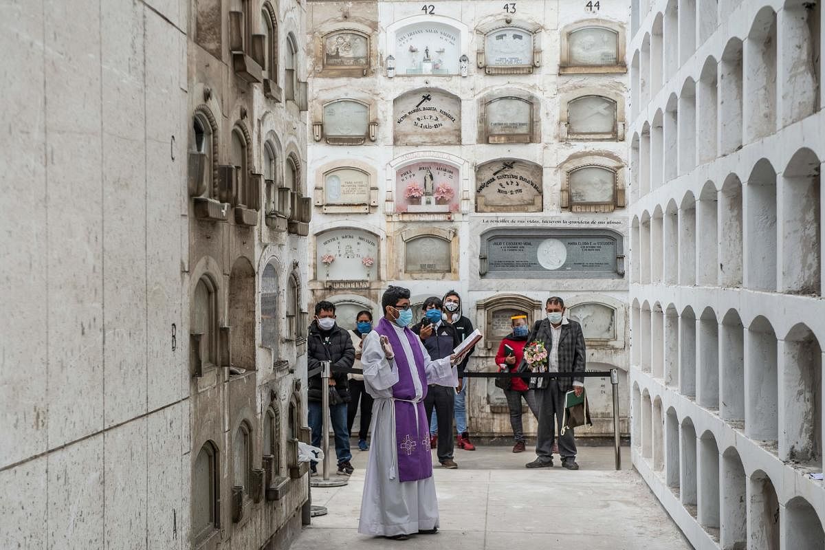 A priest conducts a ceremony after the funeral of COVID-19 victims at El Angel cemetery, in Lima on May 21, 2020. Credit: AFP Photo