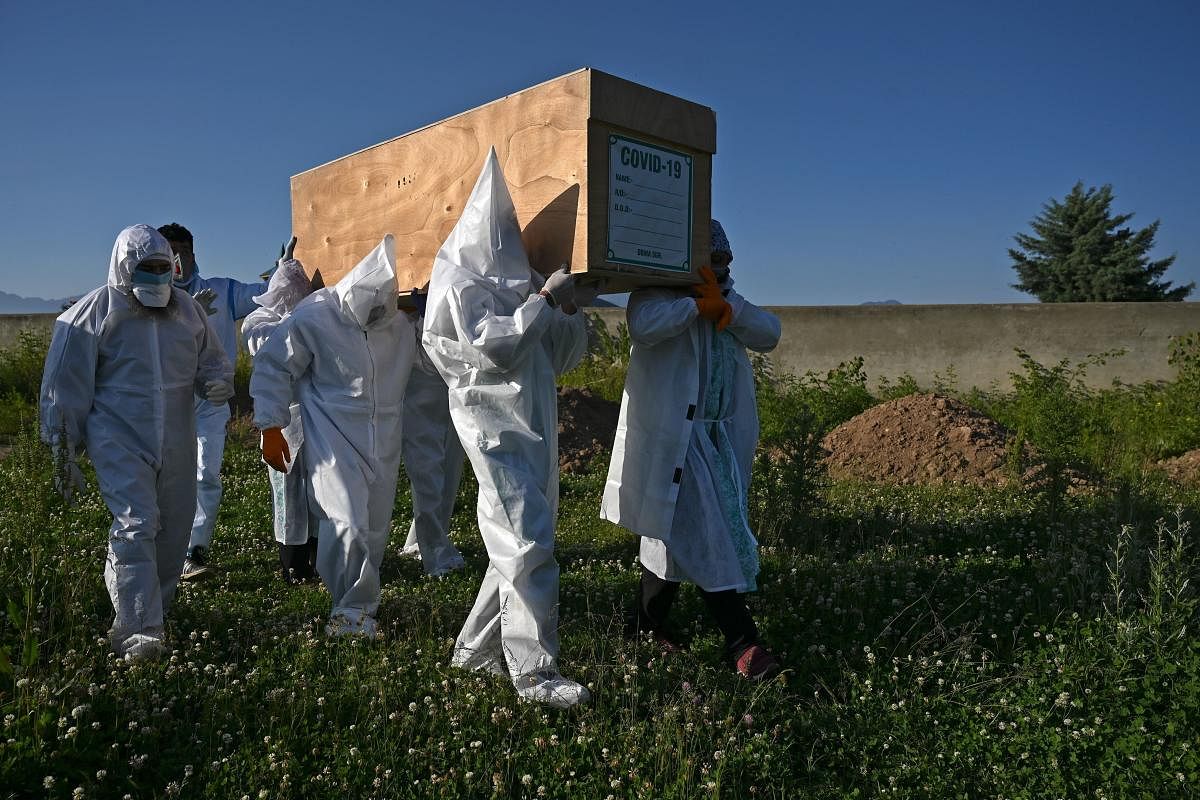 Relatives wearing Personal Protective Equipment (PPE) carry the coffin of a woman, who died from the COVID-19 coronavirus, before her burial at a graveyard in in Srinagar on May 21, 2020. Credit: AFP Photo