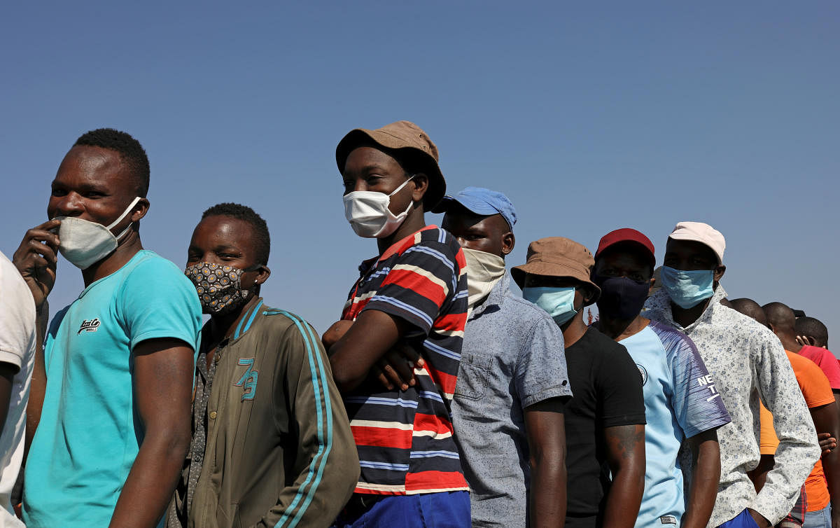People wearing protective face masks stand in a queue to receive food aid amid the spread of the coronavirus disease (COVID-19) outbreak, at the Itireleng informal settlement, near Laudium suburb in Pretoria, South Africa, May 20, 2020. Credit: Reuters Photo