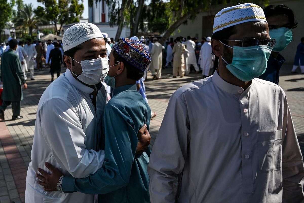 People wearing facemasks exchange greetings after offering Eid al-Fitr prayers despite concerns over the spread of the COVID-19 coronavirus at the Eidgah Sharif Darbar in Rawalpindi. (AFP Photo)