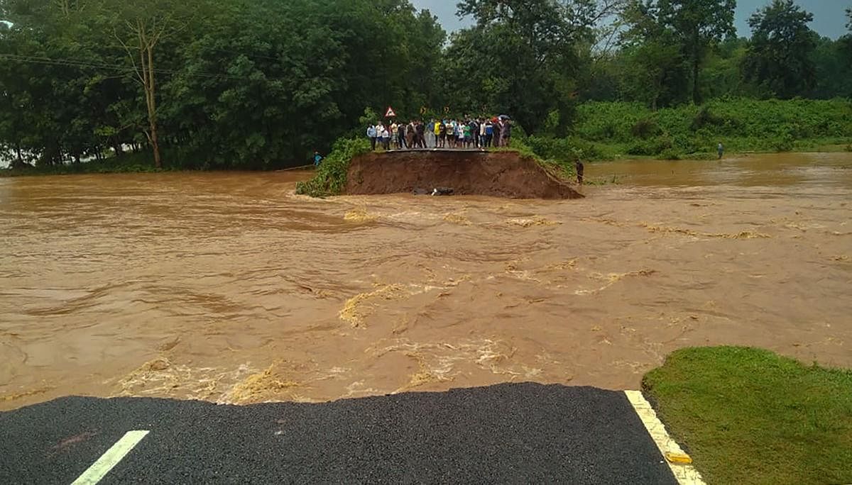 People look on after a portion of a road caved in due to flood following heavy torrential rains, at Agia-Lakhipur area in Goalpara district, Sunday, May 24, 2020. (PTI)