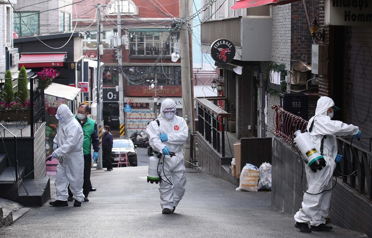 Health workers spray disinfectant on a street in the Itaewon district of Seoul (AFP Photo)