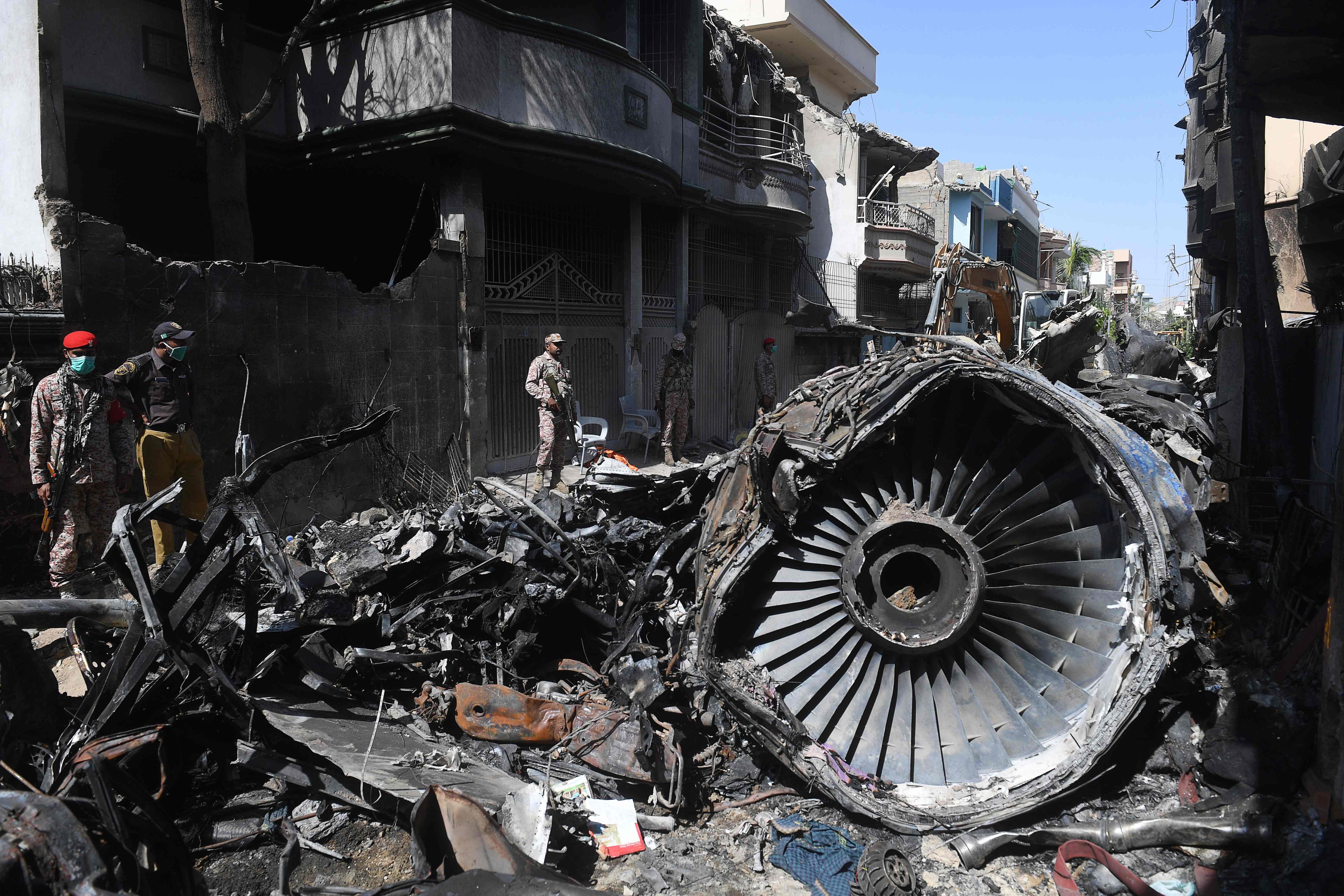 Security personnel stand beside the wreckage of a plane at the site after a Pakistan International Airlines aircraft crashed in a residential area days before, in Karachi on May 24, 2020. - Ninety-seven people were killed and two survived when a passenger plane crashed into homes in Pakistan's southern city of Karachi on May 22. (Photo by AFP)