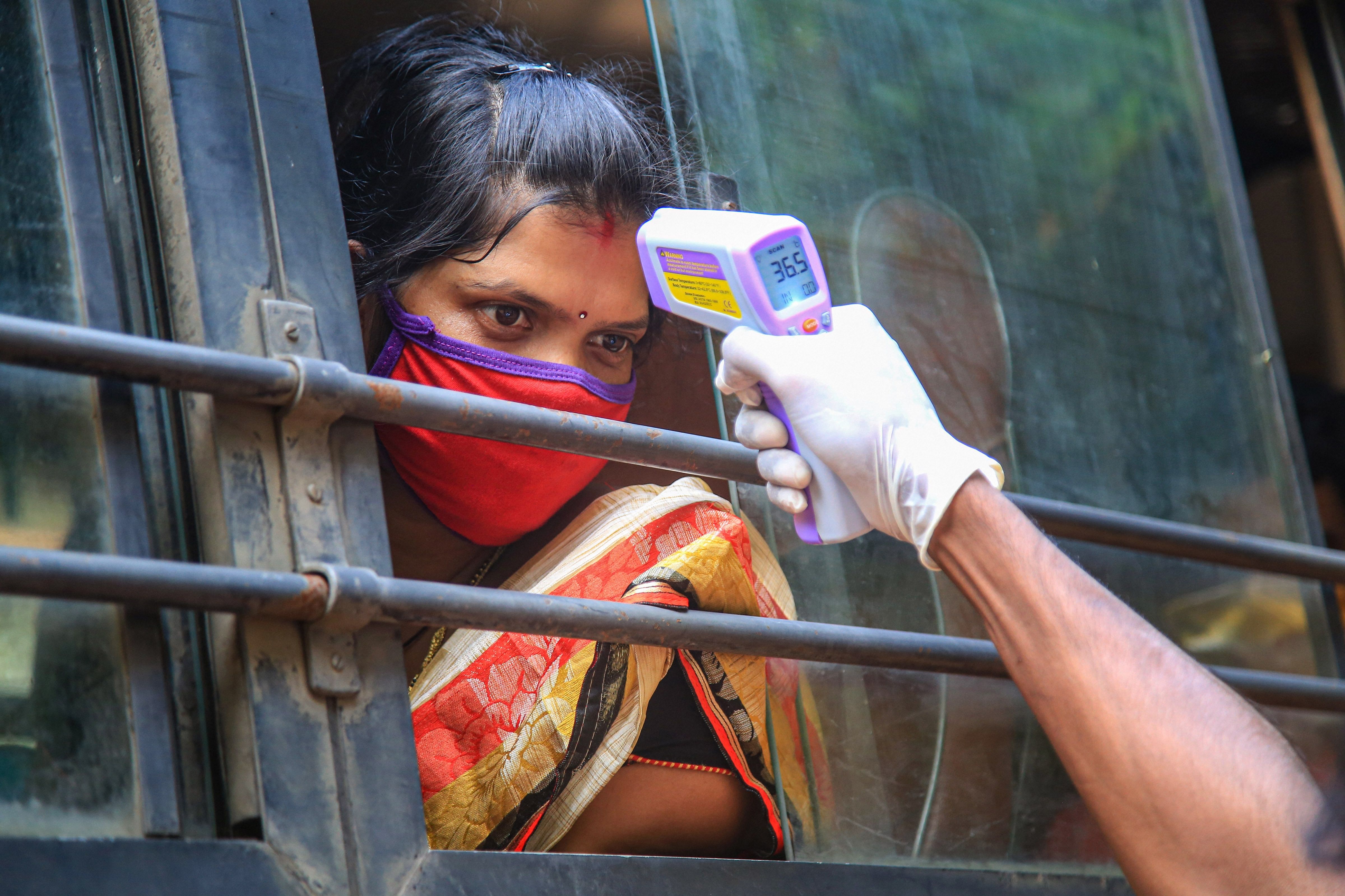 A passenger being screened as she travels in a bus to a railway station. (Credit: PTI Photo)